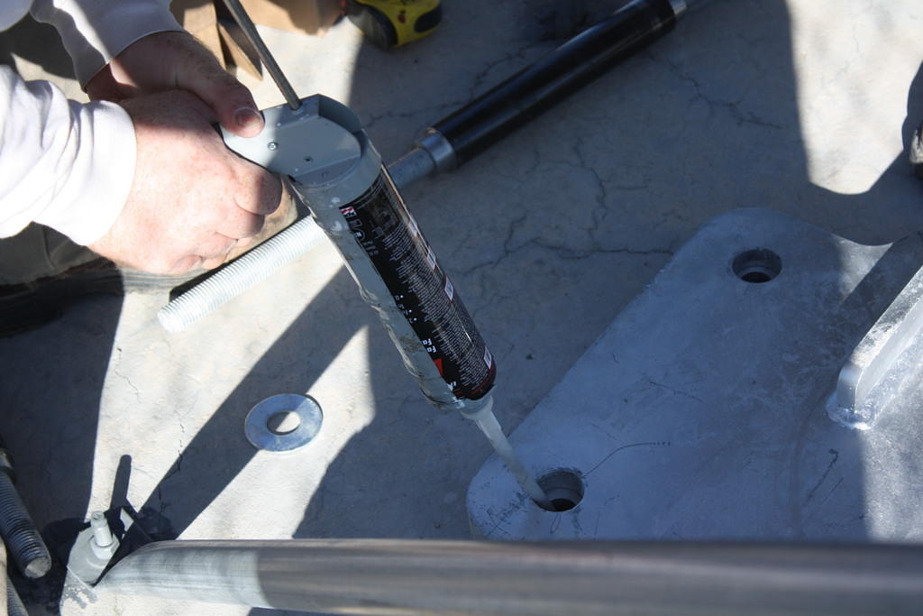 Using Epcon A7 acrylic adhesive to bond 1" all-thread galvanized steel rods to the concrete block. 12" of embeddment